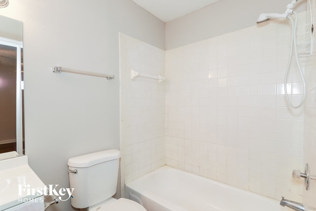 A white toilet sits next to a white bathtub in a bathroom.