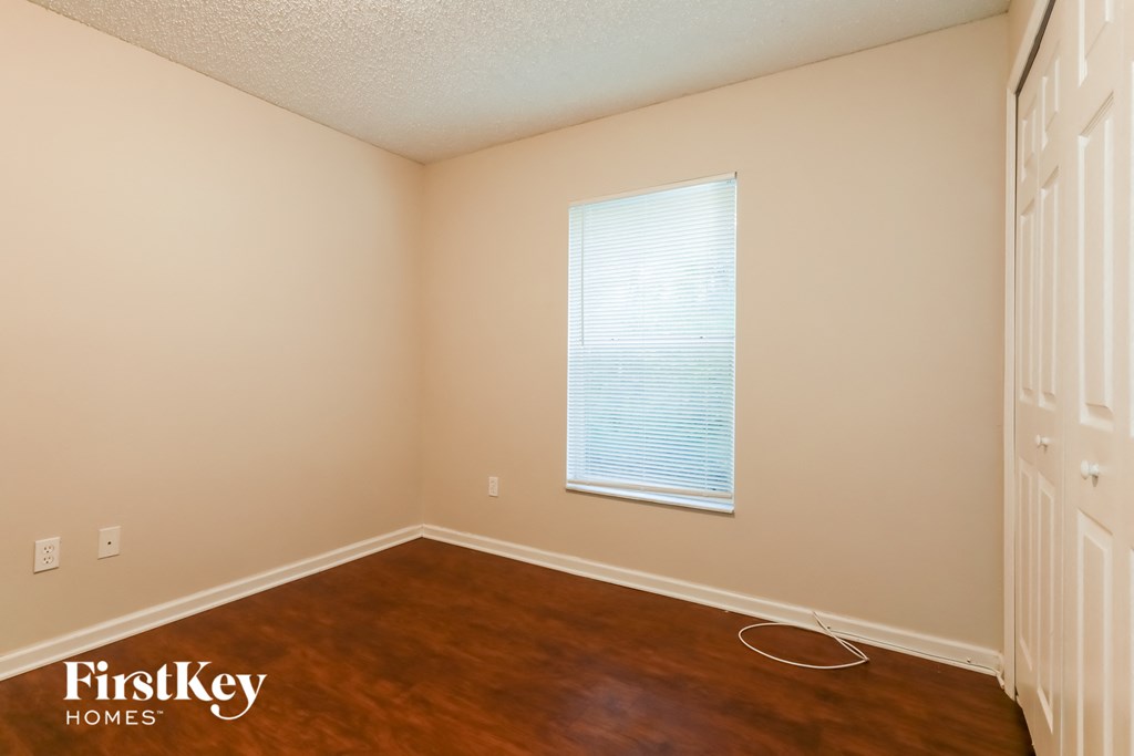 A room with a wooden floor and a window with blinds.