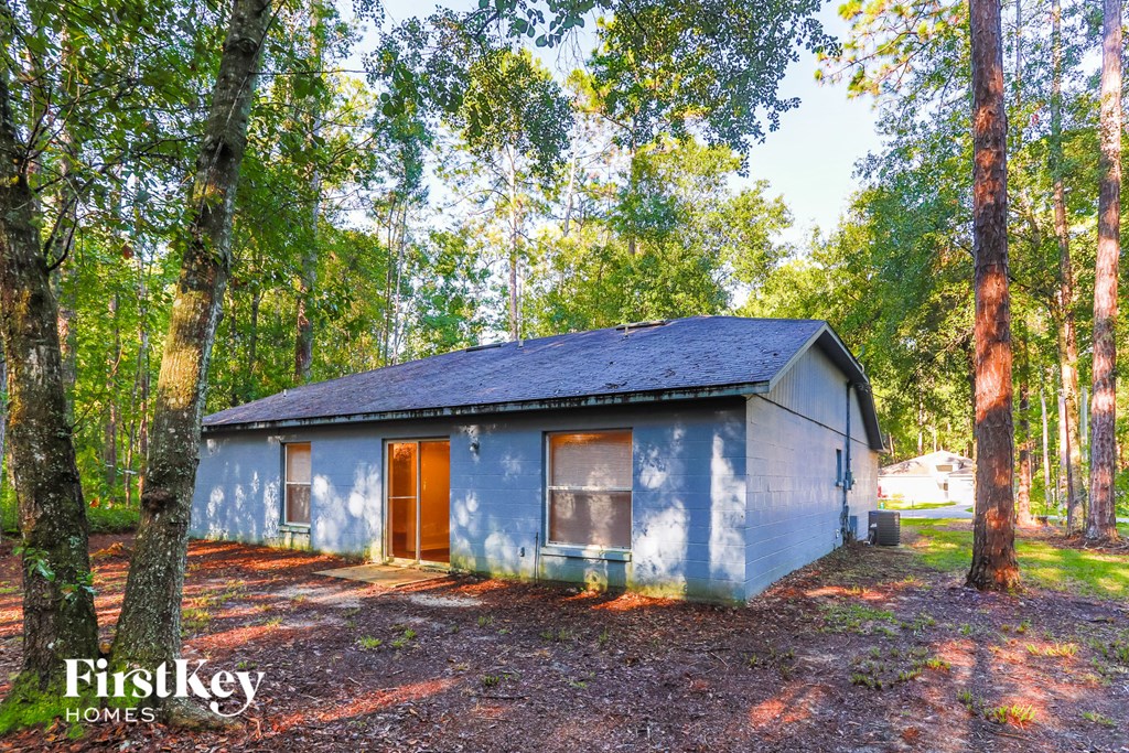 A blue house with a brown door is surrounded by trees.