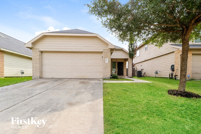 a beige house with a driveway and a tree