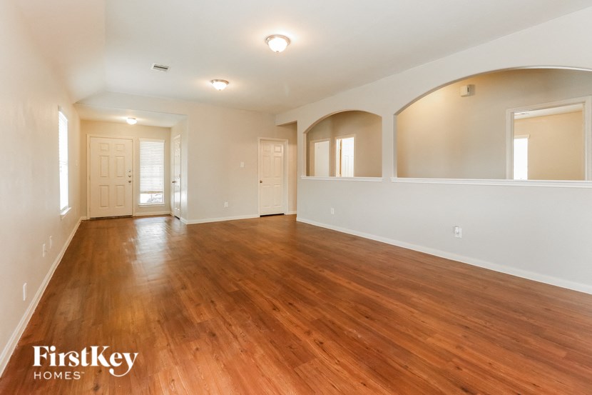 an empty living room with wood flooring and white walls
