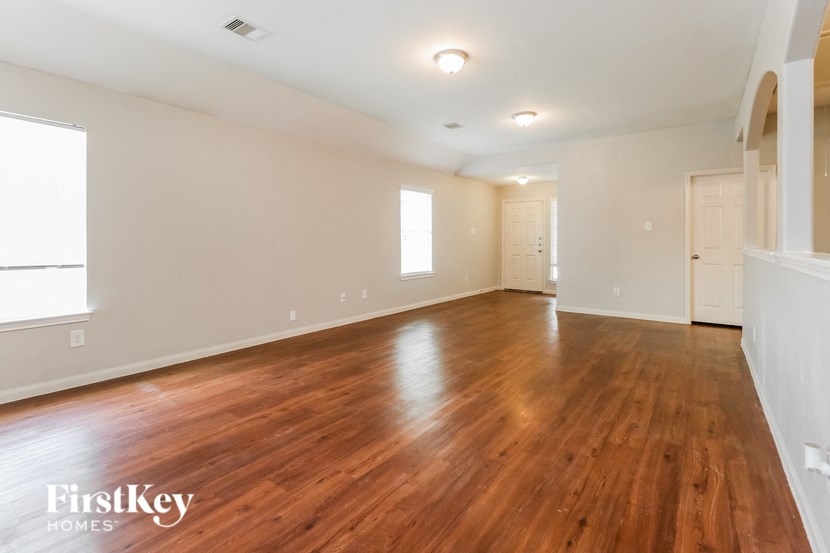 an empty living room with wood floors and white walls