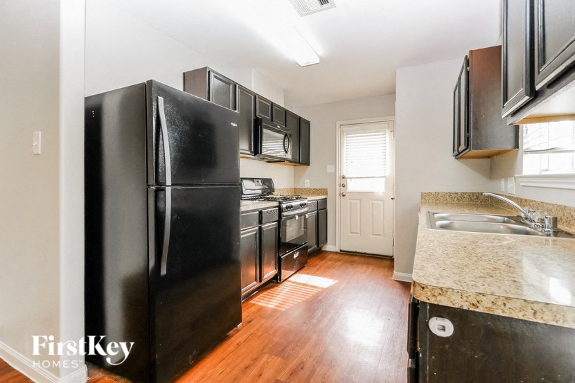 a kitchen with black appliances and a wood floor