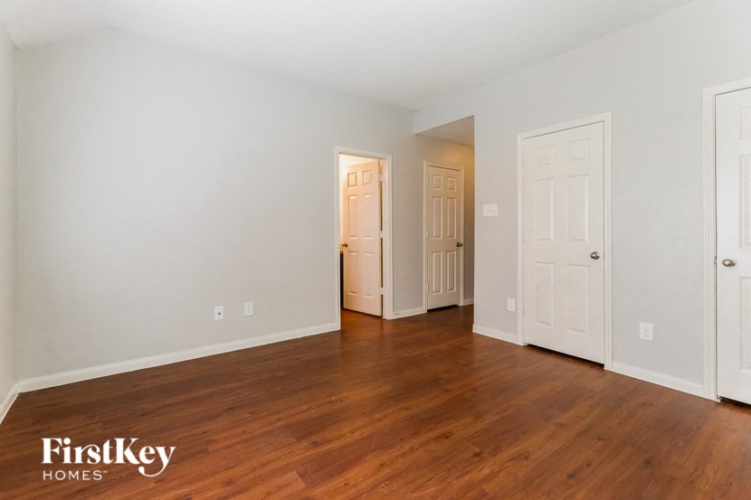 the living room of an empty house with wood floors and white doors