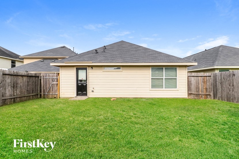 a small tan house with a yard and a fence