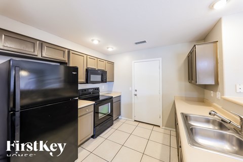 A kitchen with a black fridge and a white door.