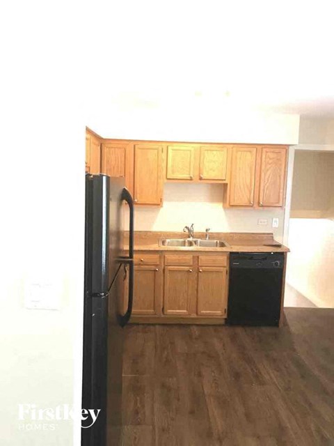 A kitchen with wooden cabinets and a black fridge.