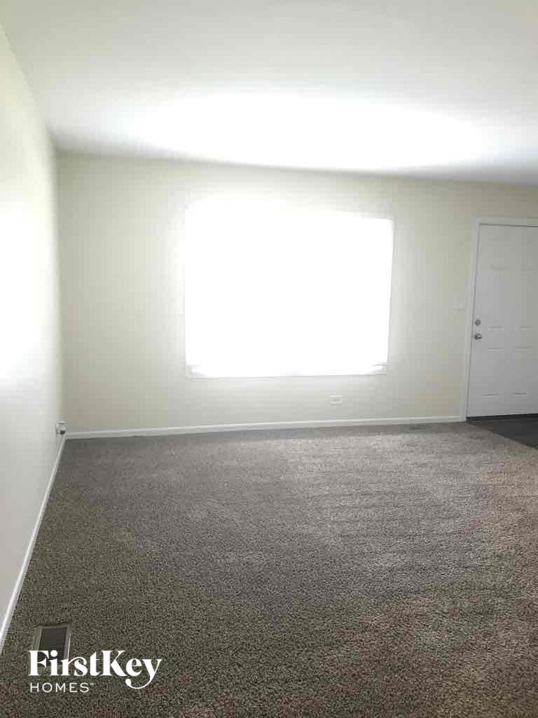 A room with a carpeted floor and a window letting in light.