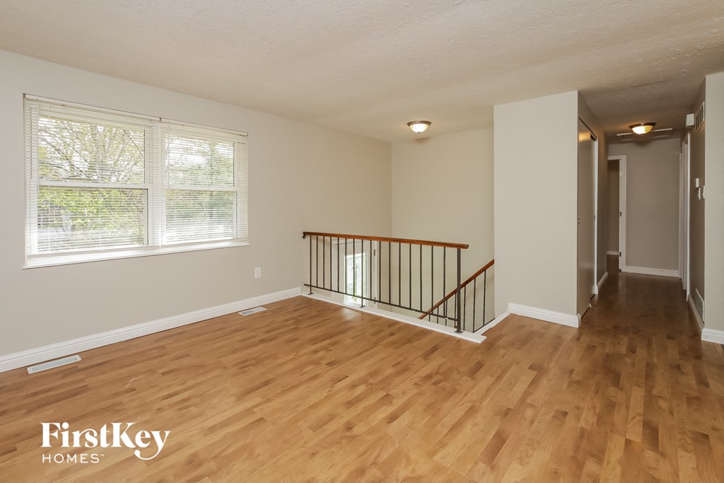 A room with wooden floors and a balcony with a railing.