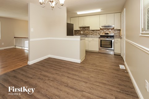 A kitchen with wooden floors and a stone backsplash.