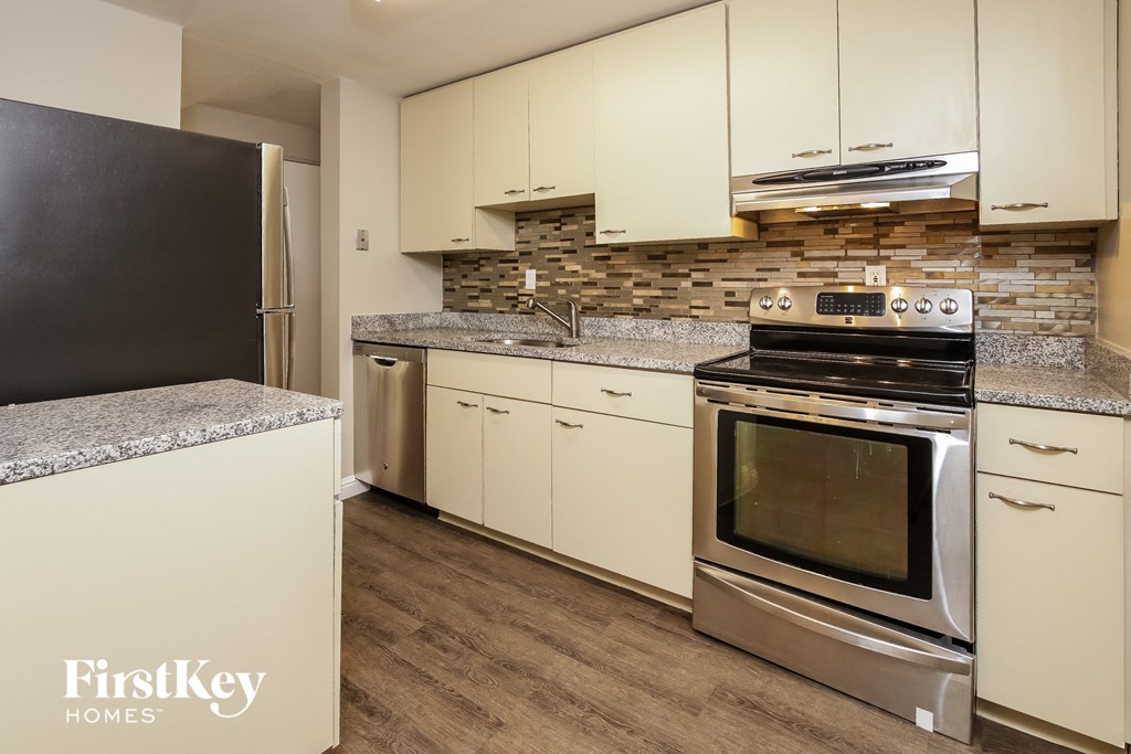 A kitchen with a black fridge and a stainless steel oven.