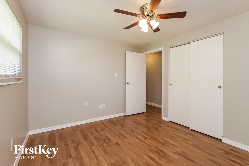 A room with a ceiling fan and wooden floors.