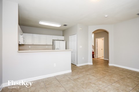 A spacious kitchen area with white cabinets and a tiled floor.