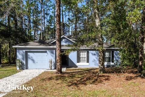A blue house with a garage is surrounded by trees.