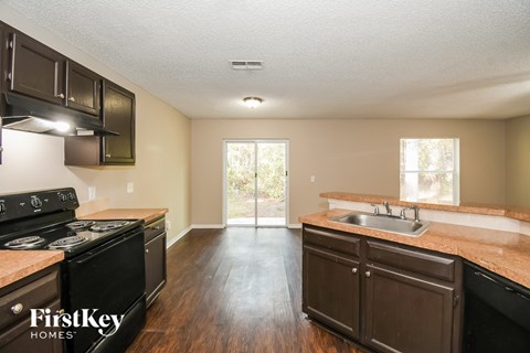 A kitchen with dark wood cabinets and a black stove top oven.