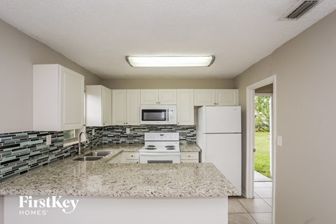 a kitchen with white cabinets and granite counter tops and a white refrigerator
