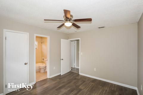 a living room with a ceiling fan and a door to a bathroom