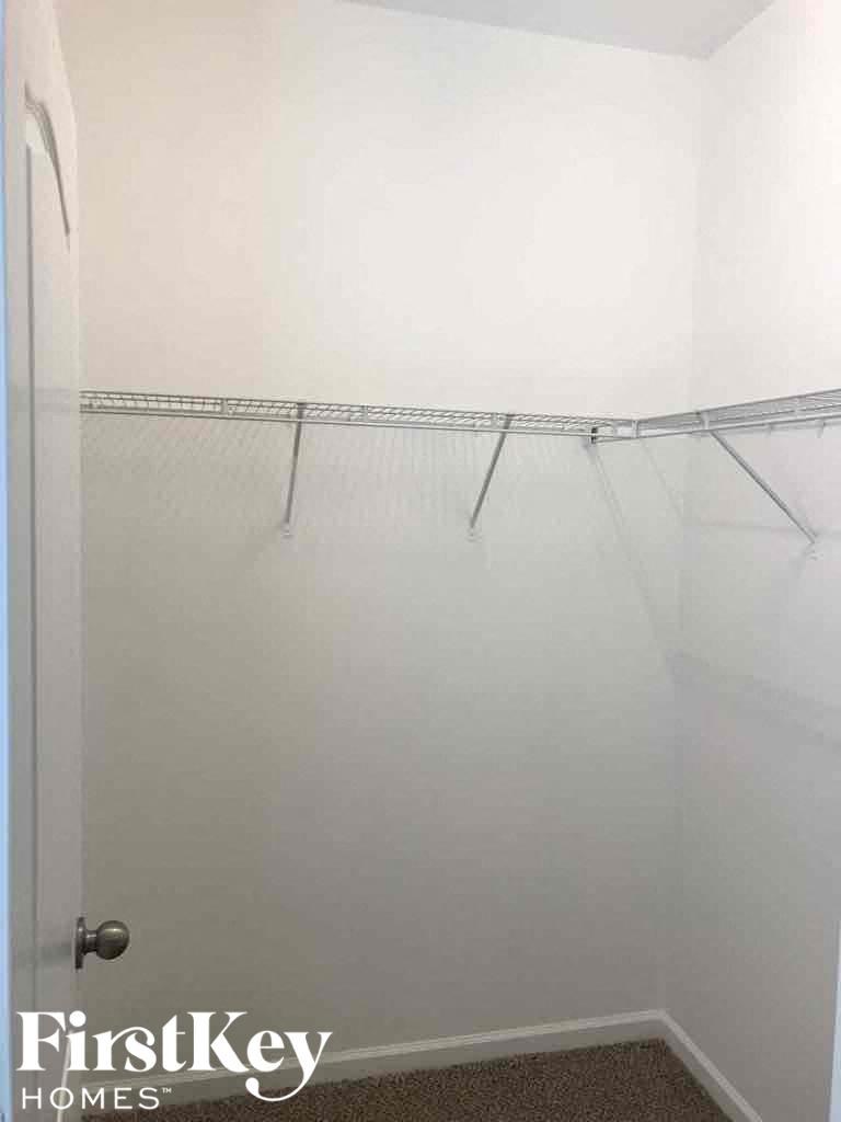 A white closet with a metal rod and a door.