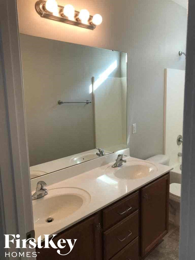 A bathroom with a mirror, two sinks and a lighted wall.