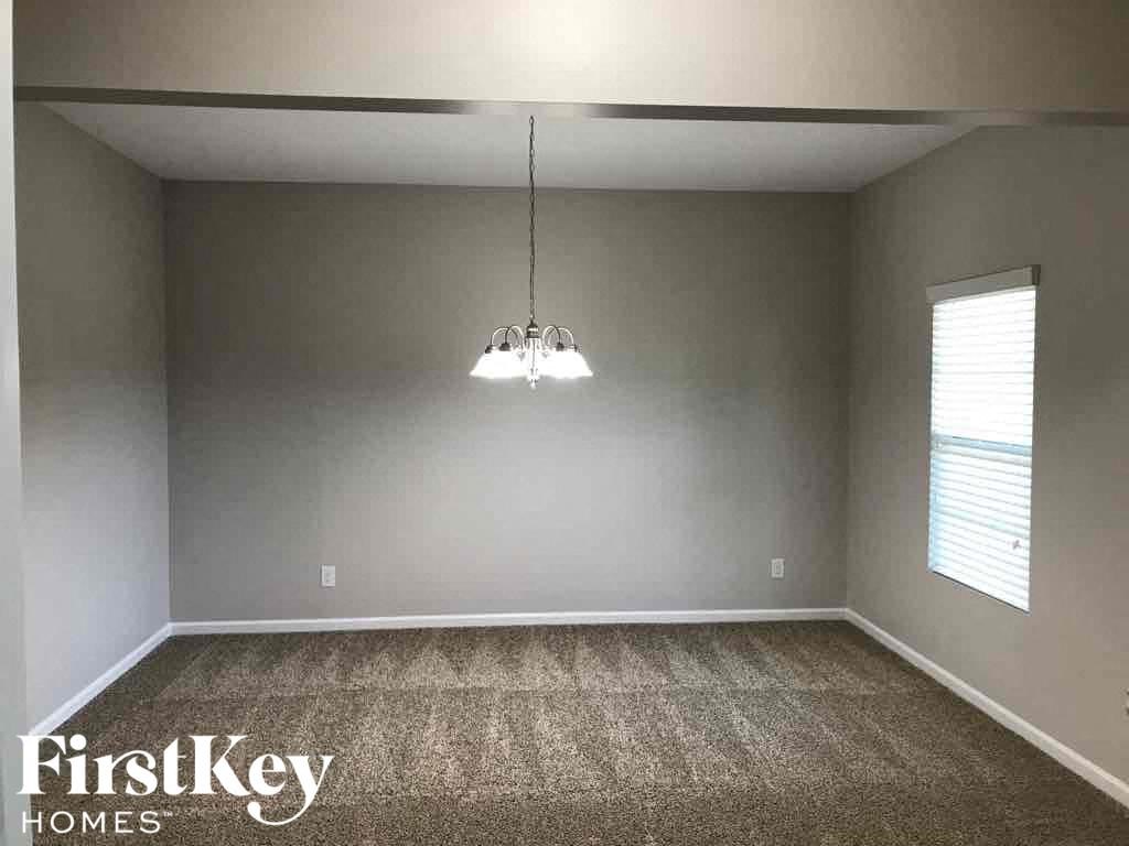 A room with a carpeted floor and a hanging light fixture.