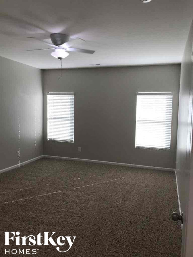 A room with a carpet floor and a ceiling fan.
