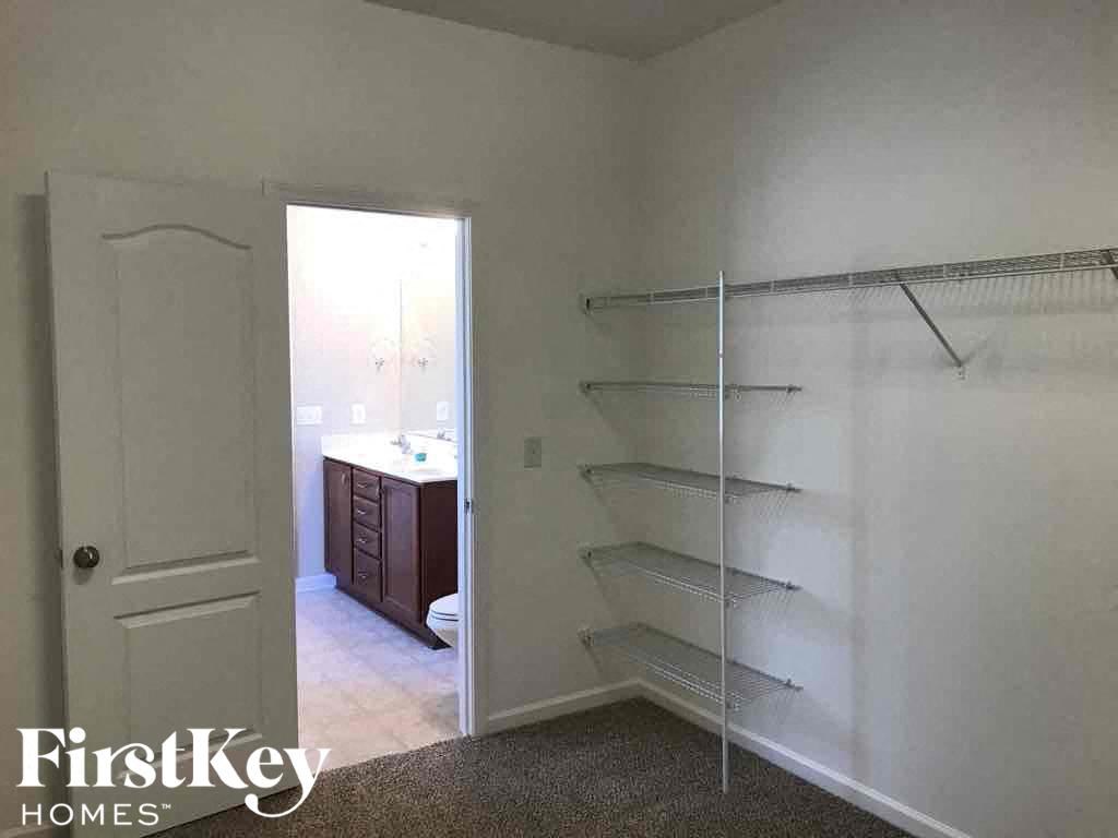 A white room with a door and a shelf.