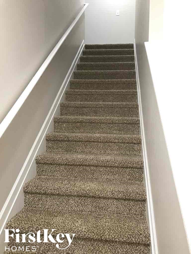 A staircase with a carpeted runner and a metal handrail.