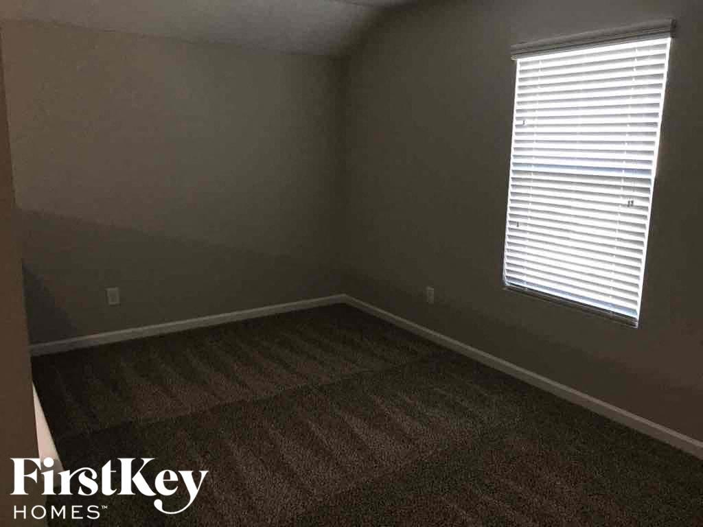 A room with a carpeted floor and a window with blinds.