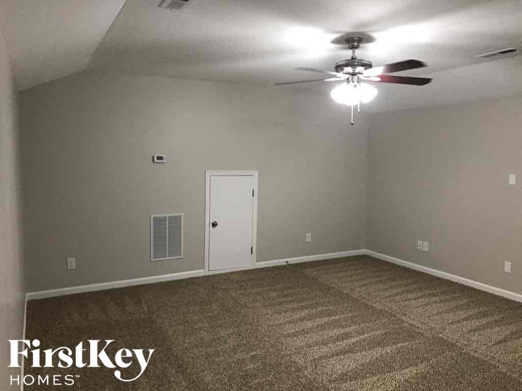 A room with a carpeted floor and a ceiling fan.
