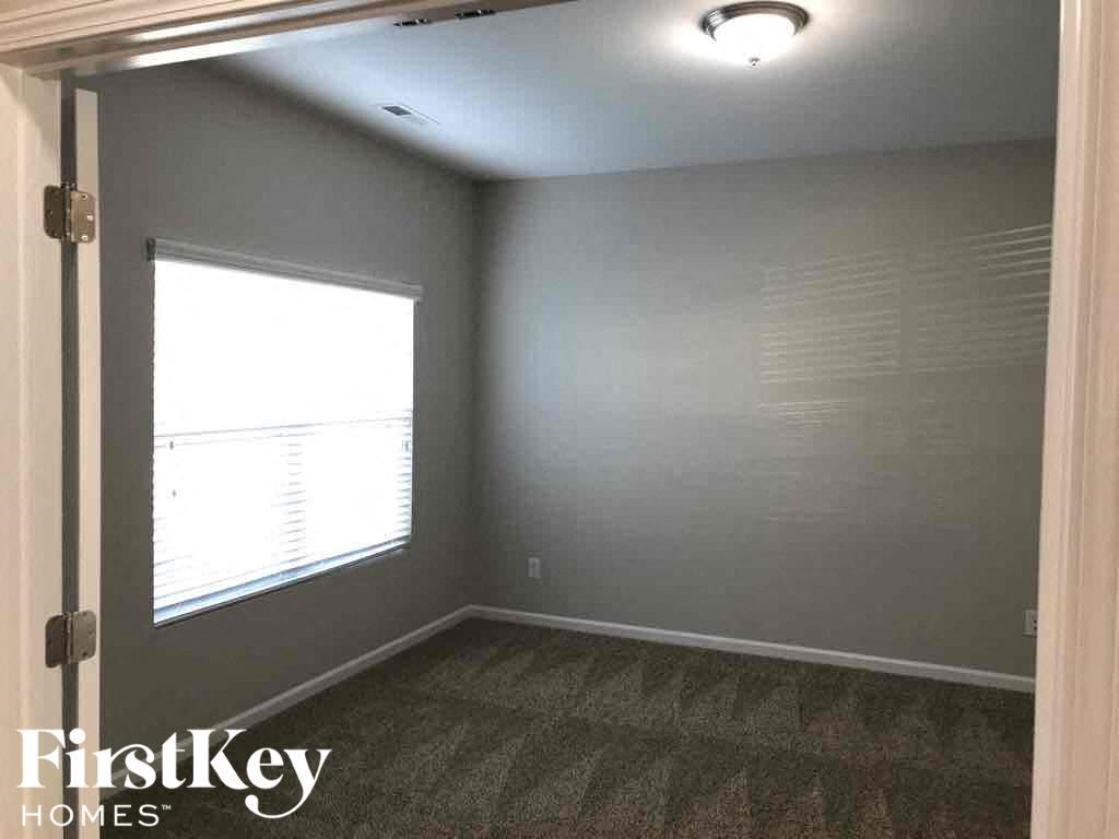A room with a window covered by blinds and a carpet on the floor.