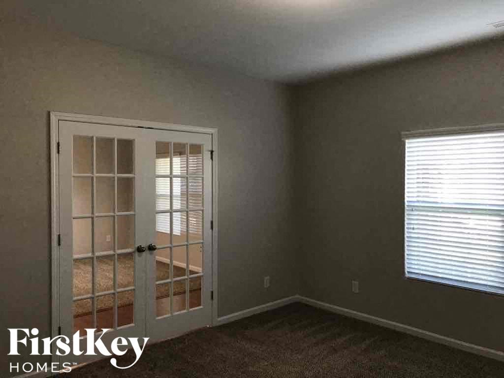 A room with a carpeted floor, a door with a glass panel, and a window with blinds.