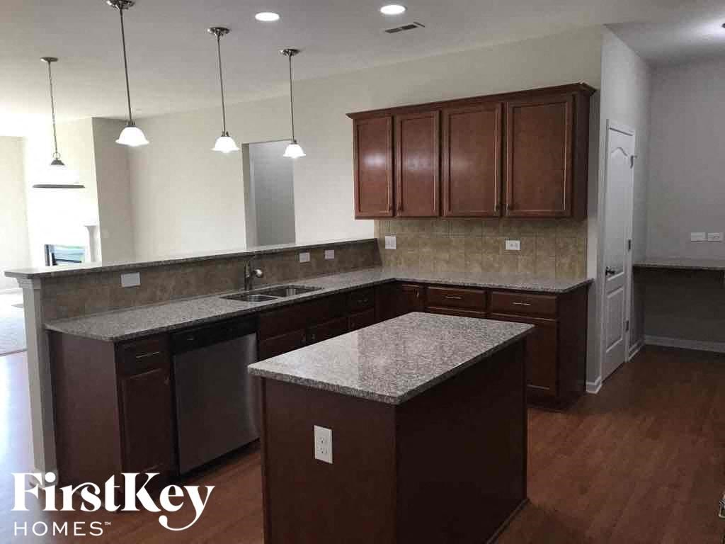A kitchen with brown cabinets and a granite countertop.