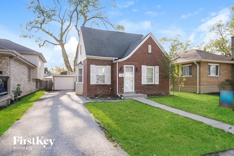 a small brick house with a driveway and lawn