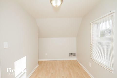 a living room with white walls and a window and a wooden floor