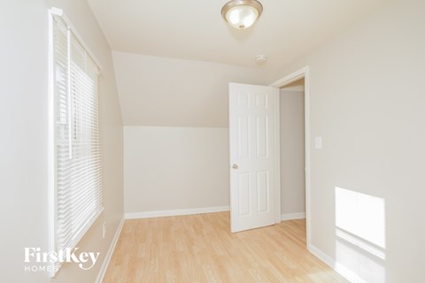 a bedroom with white walls and a white door and wood floors
