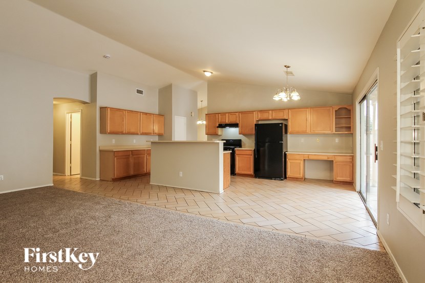 A spacious kitchen with wooden cabinets and a black refrigerator.