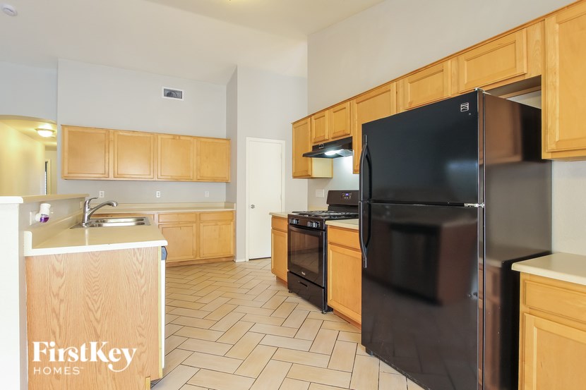 A kitchen with a black refrigerator and wooden cabinets.