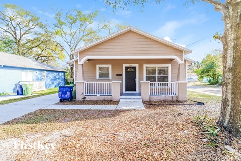 a small tan house with a front porch and a blue mailbox