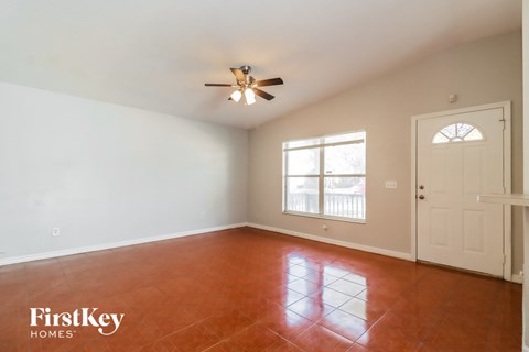 an empty living room with a white door and a ceiling fan