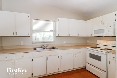 a kitchen with white cabinets and white appliances and a sink