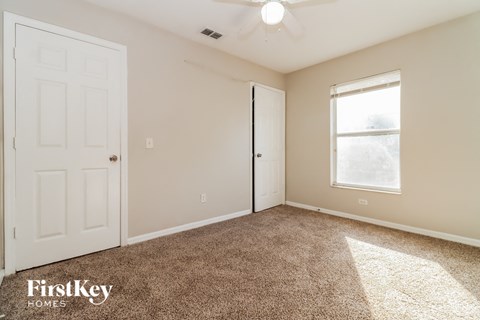 a bedroom with carpet and a white door and window