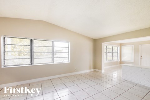 A spacious room with a large window and a tiled floor.