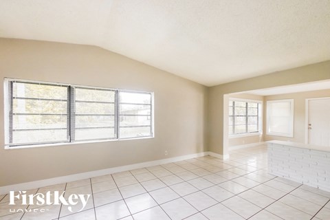 A spacious room with a large window and a tiled floor.