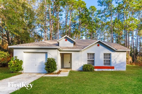 a white house with a garage door and a lawn