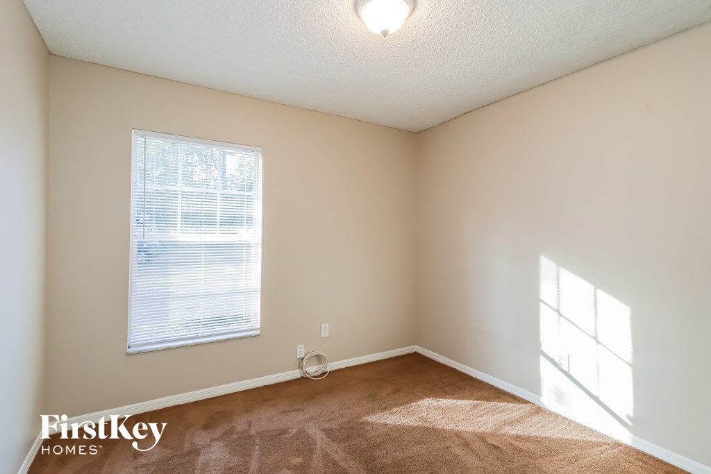 a bedroom with a window and a carpeted floor