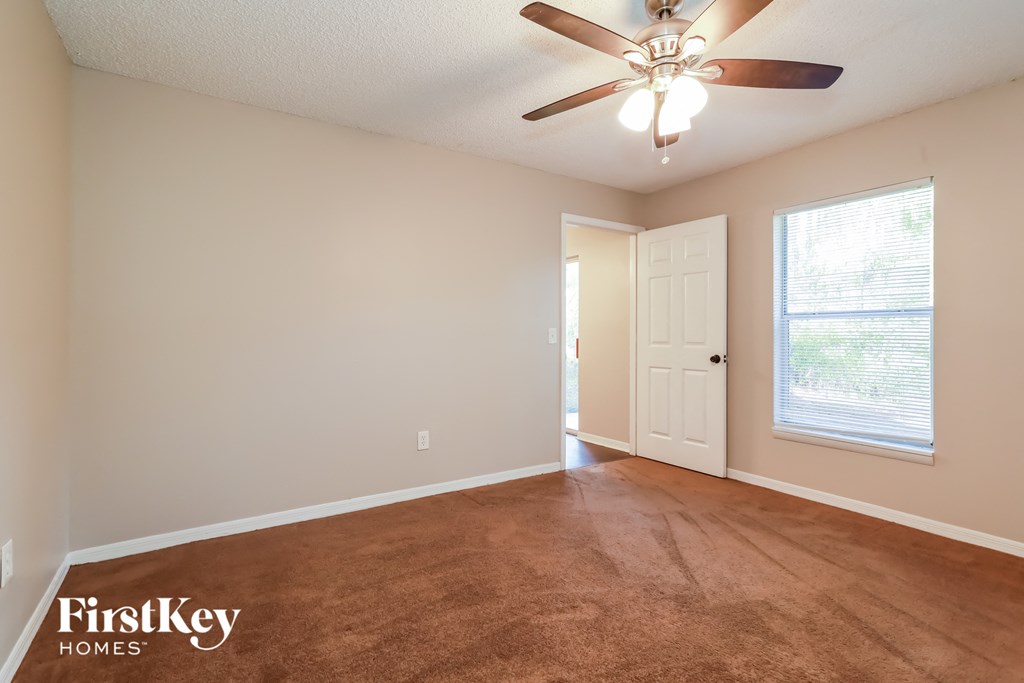 an empty living room with a ceiling fan and a window