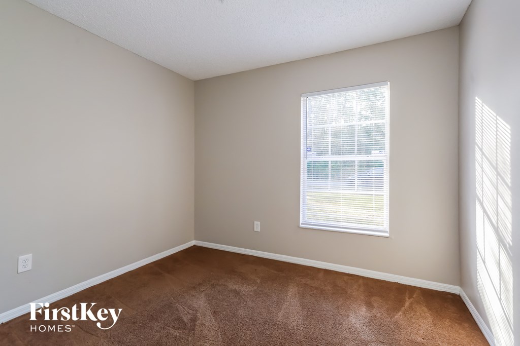 an empty room with a window and a carpeted floor
