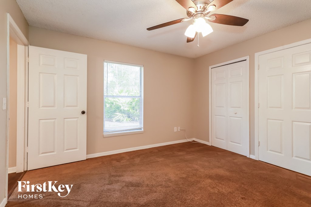 the master bedroom has a carpeted floor and a ceiling fan