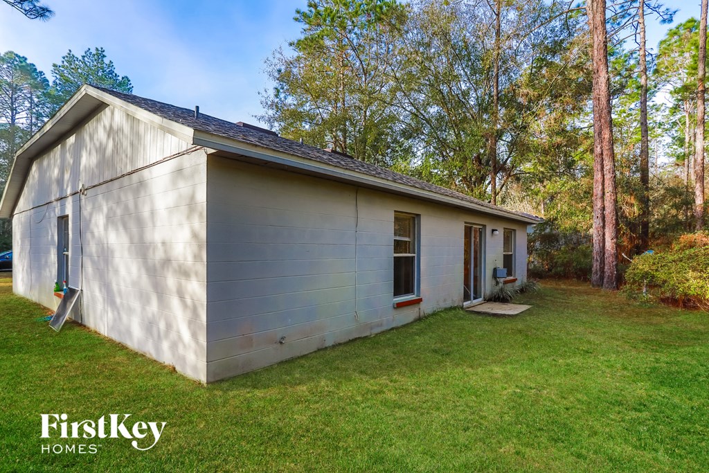 a small white house with a yard and trees