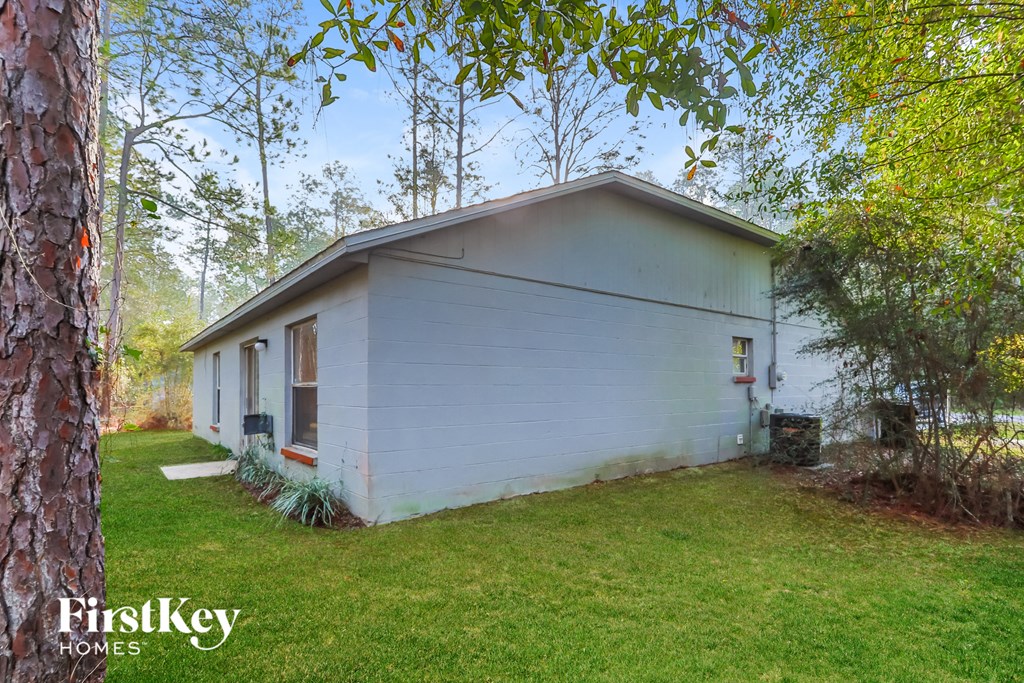 a small white house in the middle of a yard with trees